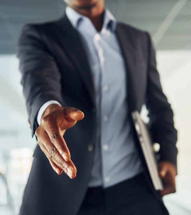 Successfull agreement. Young african american businessman in black suit is indoors.